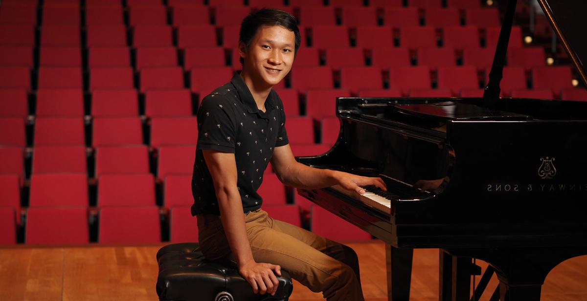 十大玩彩信誉平台的学生Paul Nguyen站在校园莱德劳表演艺术中心的钢琴前.